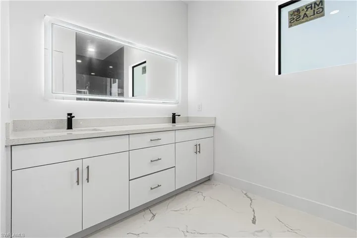 Full bath with marble finish floors and double vanity