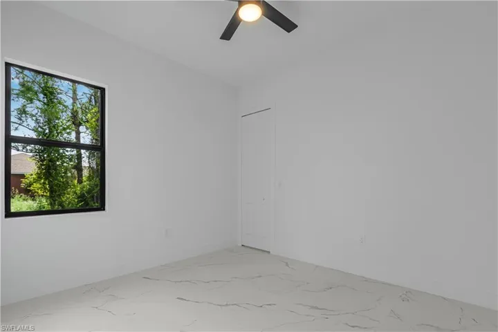 Spare room with light marble finish flooring and a ceiling fan