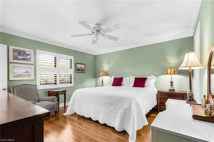Bedroom featuring wood finished floors, ornamental molding, and ceiling fan