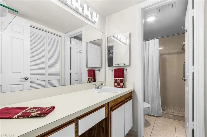 Bathroom with vanity, a stall shower, light tile patterned floors, and a closet