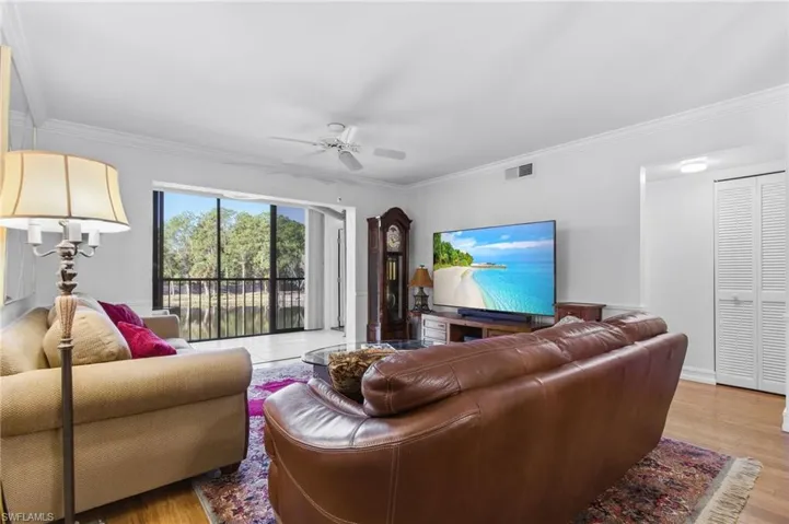 Living area with a ceiling fan, light wood-style floors, and ornamental molding
