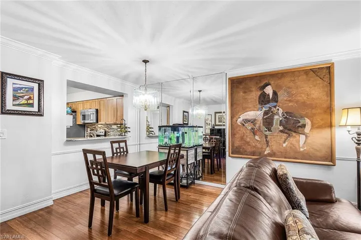 Dining area with crown molding, suspended lighting, and wood-type flooring