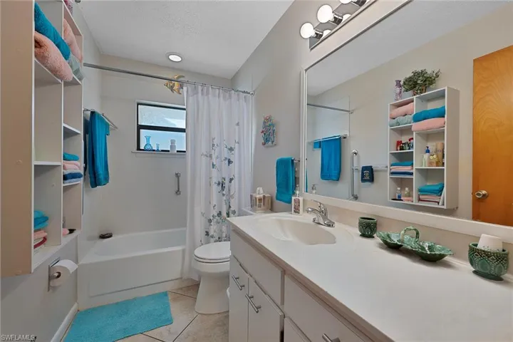 Bathroom with light tile patterned floors, shower / bath combo with shower curtain, vanity, and a textured ceiling