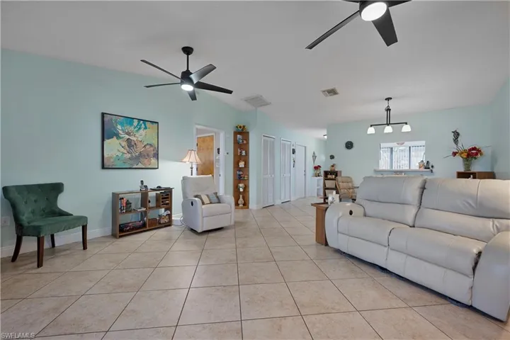 Living area featuring lofted ceiling, light tile patterned floors, and a ceiling fan