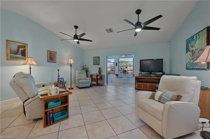 Living area featuring lofted ceiling, light tile patterned floors, and a ceiling fan
