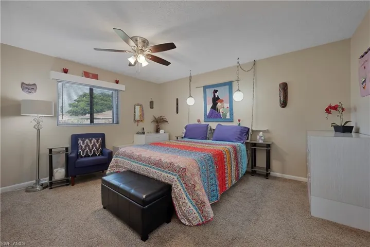 Bedroom with light carpet, a ceiling fan, and a textured ceiling