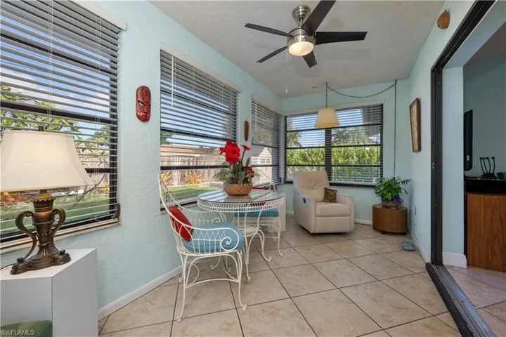 Sunroom featuring a textured wall, tile patterned flooring, a textured ceiling, ceiling fan, and a patio area