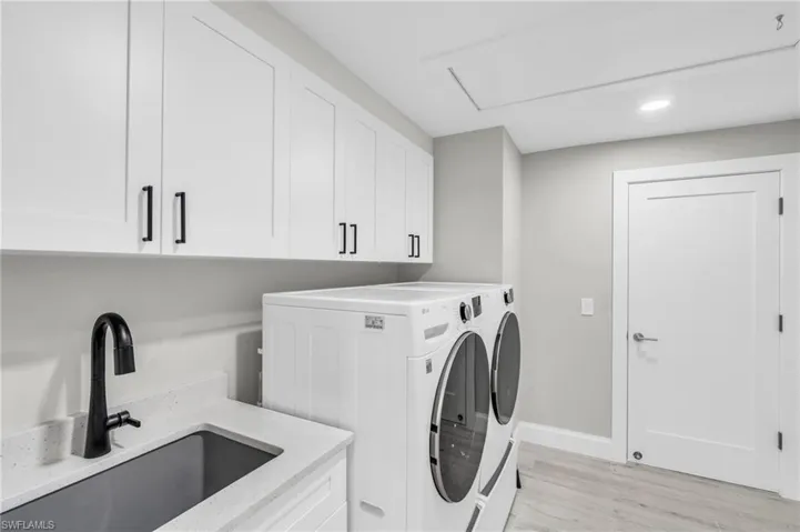 Functional laundry space featuring a sink, countertop, and overhead cabinets - Virtually Edited Image