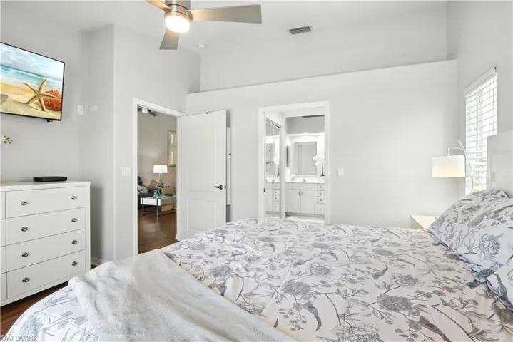 Bedroom with multiple windows, dark wood-type flooring, and ensuite bathroom