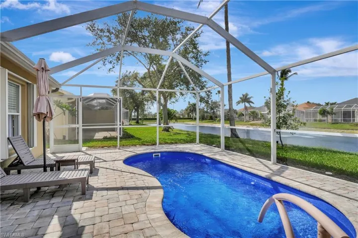 Outdoor pool with a patio, a sunroom, a water view, and glass enclosure