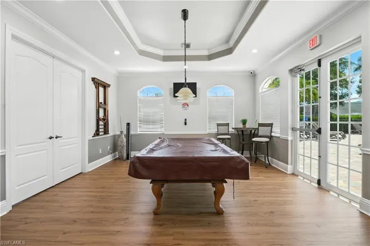 Playroom featuring billiards table, ornamental molding, a raised ceiling, wood finished floors, and recessed lighting