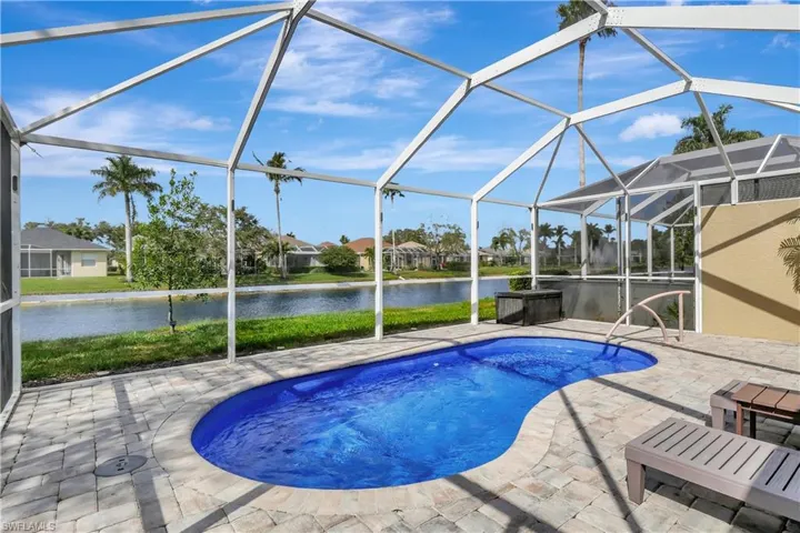 Outdoor pool with a sunroom, a water view, glass enclosure, and a patio