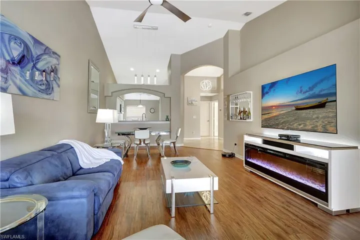 Living area featuring high vaulted ceiling, wood finished floors, and ceiling fan