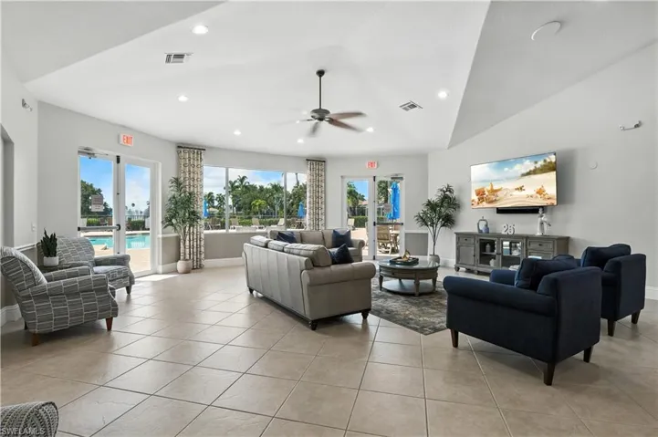 Living room with plenty of natural light, lofted ceiling, light tile patterned floors, recessed lighting, and ceiling fan