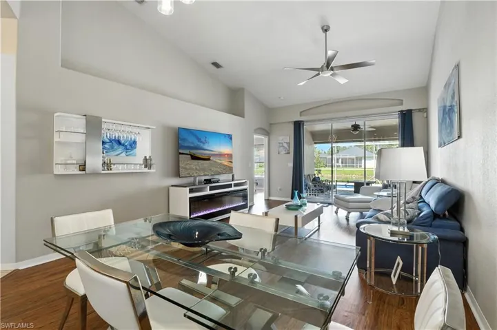 Dining area with a ceiling fan, wood finished floors, high vaulted ceiling, and arched walkways