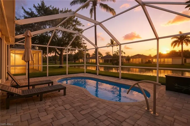 Pool at dusk featuring an outdoor pool, a sunroom, a water view, a patio area, and a yard