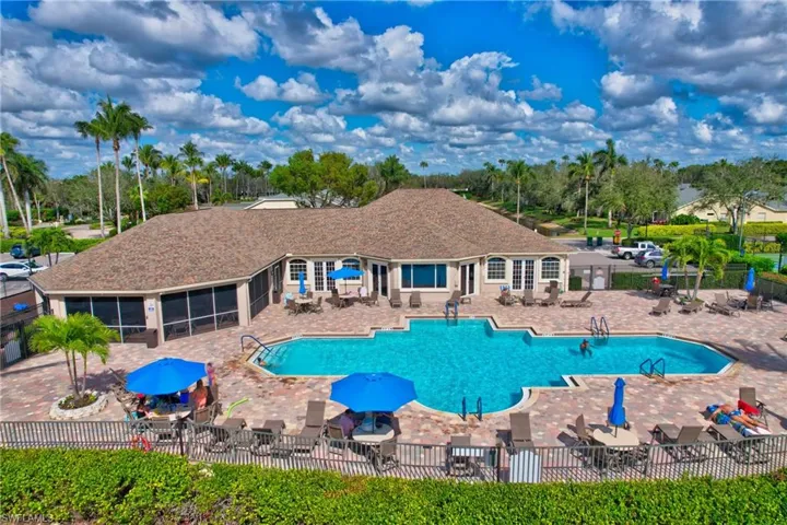 Community pool featuring a patio, view of wooded area, and a sunroom