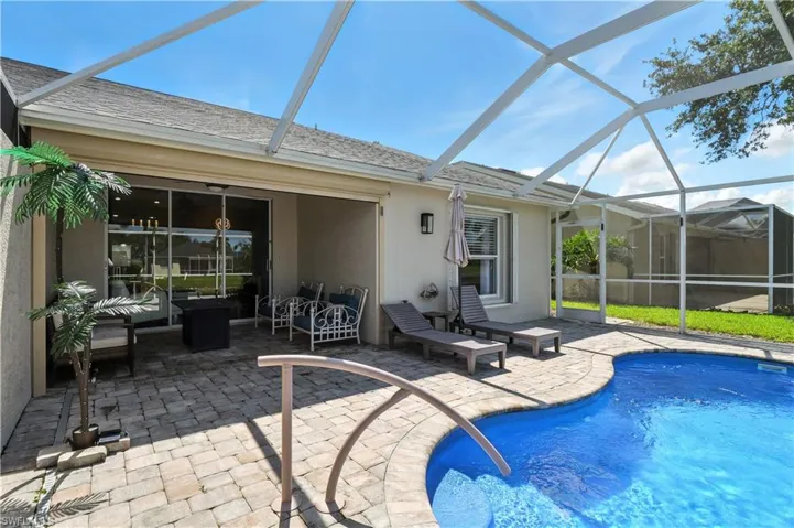 Outdoor pool with a sunroom, glass enclosure, and a patio
