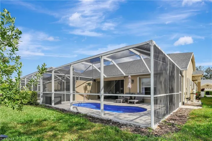 Back of property with a sunroom, a lanai, an outdoor pool, a shingled roof, and a patio area