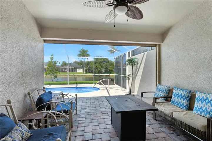 View of patio / terrace featuring a sunroom, a water view, an outdoor pool, a ceiling fan, and glass enclosure