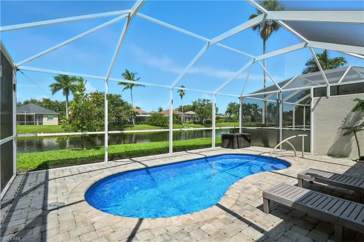 Swimming pool featuring a sunroom, a water view, a patio area, and a lanai