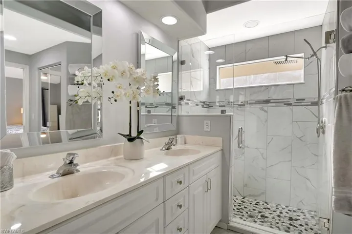 Full bath with a marble finish shower and double vanity