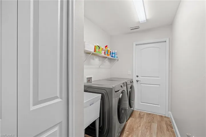 Clothes washing area with independent washer and dryer and light hardwood / wood-style floors