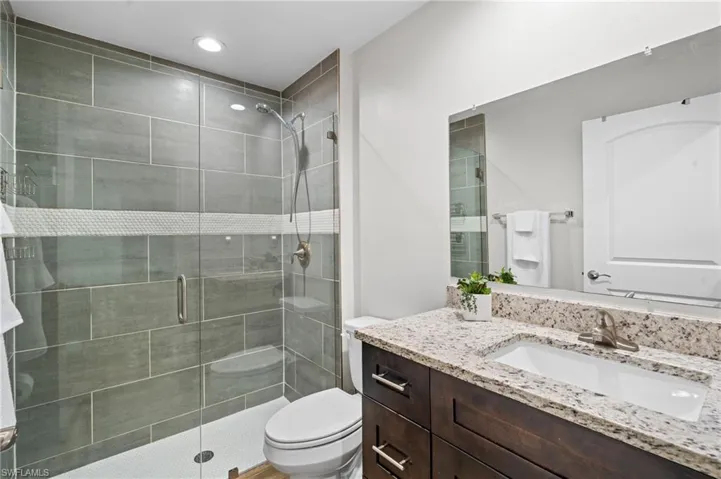 Bathroom with vanity, toilet, and a shower with door