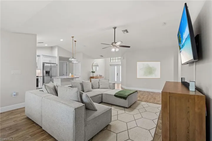 Living room with ceiling fan, light hardwood / wood-style floors, lofted ceiling, and french doors