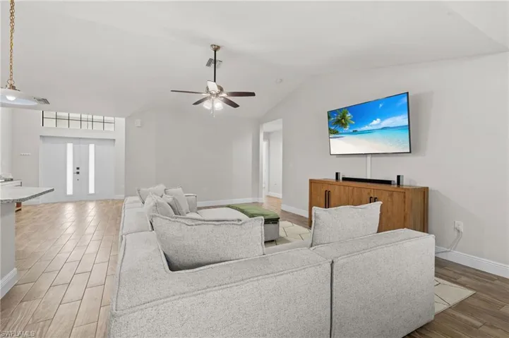 Living room with wood-type flooring, ceiling fan, and lofted ceiling