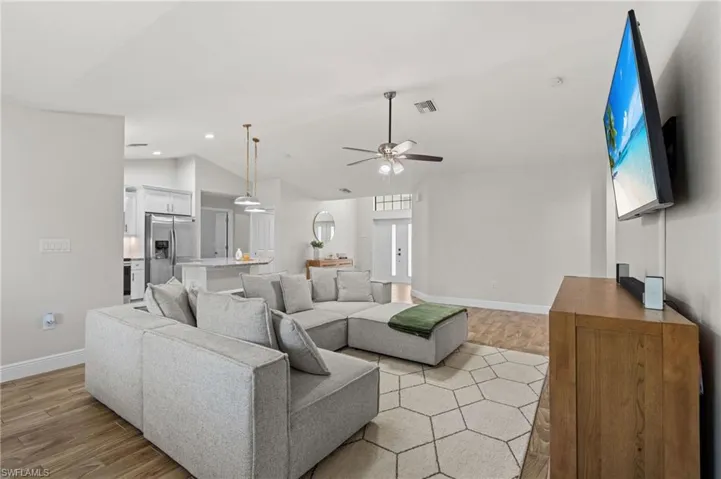 Living room with ceiling fan, light hardwood / wood-style floors, and vaulted ceiling