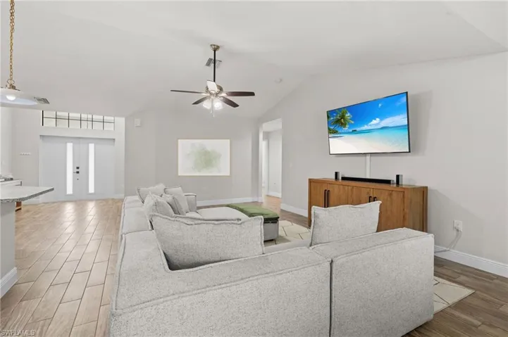Living room with wood-type flooring, ceiling fan, and lofted ceiling