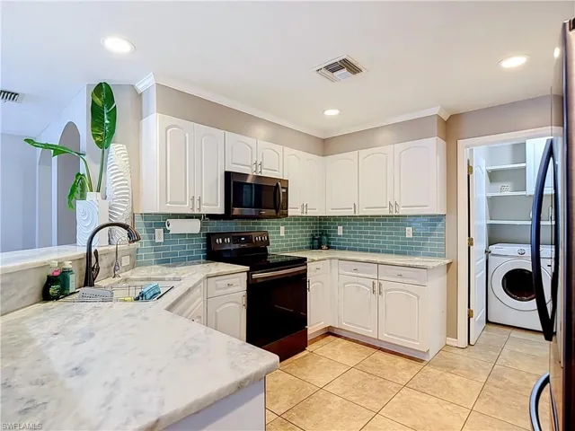 Kitchen featuring white cabinetry, light-toned countertops, a blue subway tile backsplash, and recessed lighting