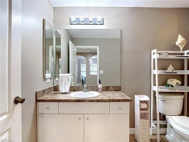 Bathroom vanity featuring a white undermount sink, a brown speckled countertop, and white cabinetry with clear knobs