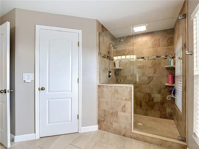Tiled walk-in shower with a glass enclosure, integrated shelving, and a mosaic floor