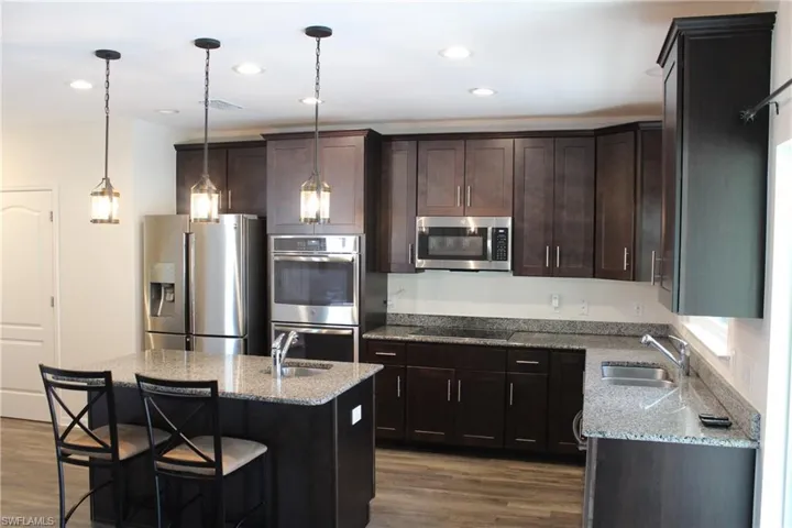 Kitchen with stainless steel appliances, sink, vinyl floors, and a kitchen island