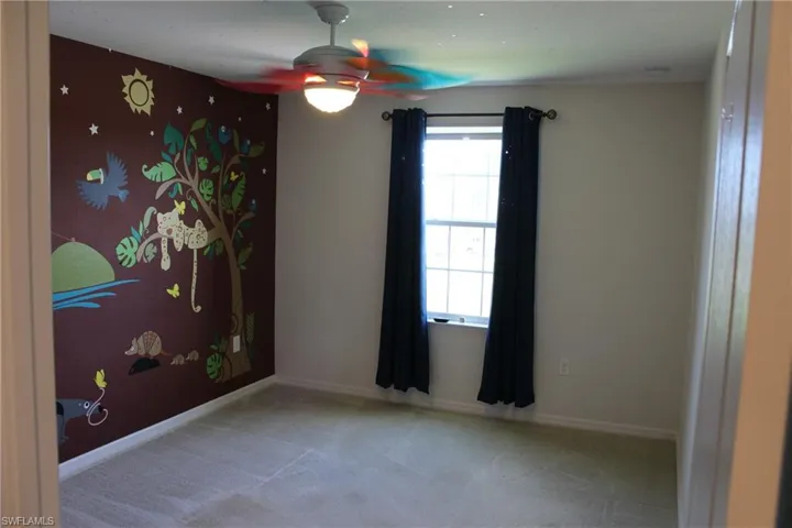 Carpeted empty room featuring ceiling fan