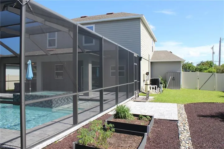 Rear view of property featuring a patio, glass enclosure, and a fenced in pool
