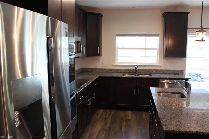 Kitchen with sink, decorative light fixtures, dark hardwood / wood-style floors, and stainless steel appliances
