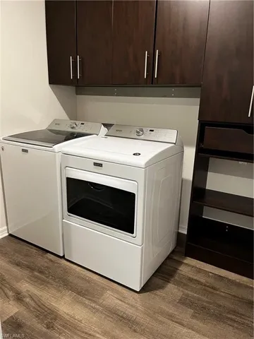 Laundry room with cabinets, hardwood / wood-style flooring, and washing machine and clothes dryer