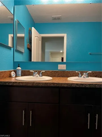 Bathroom featuring double sink vanity and a textured ceiling