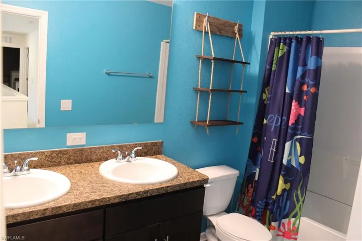 Bathroom with toilet and dual bowl vanity