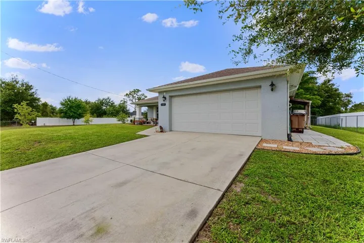 View of property exterior featuring a garage and a lawn