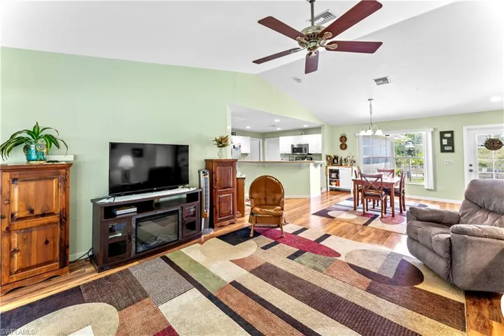 Living room featuring wood-type flooring, vaulted ceiling, and ceiling fan with notable chandelier