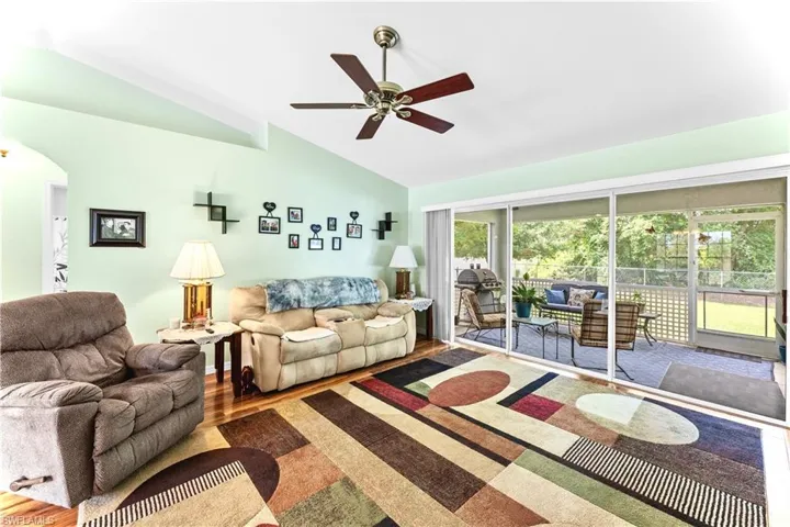 Living room with lofted ceiling, ceiling fan, and hardwood / wood-style floors