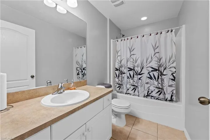Full bathroom with tile floors, toilet, oversized vanity, and shower / bath combo with shower curtain