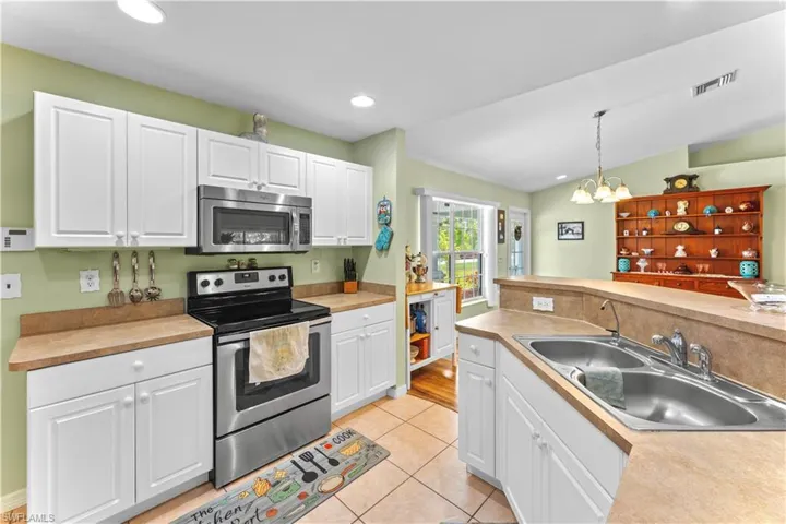 Kitchen with sink, white cabinets, pendant lighting, and stainless steel appliances