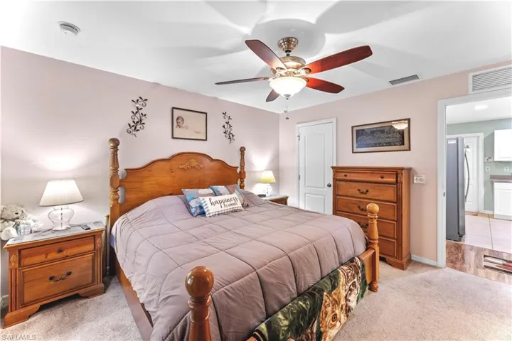 Carpeted bedroom featuring stainless steel refrigerator and ceiling fan