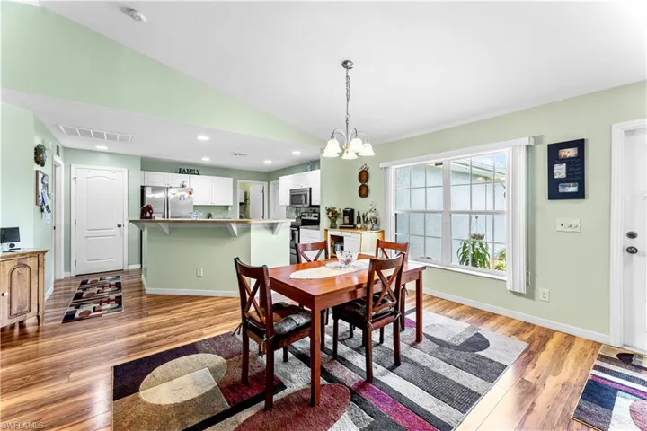 Dining space featuring a chandelier, vaulted ceiling, and light hardwood / wood-style flooring