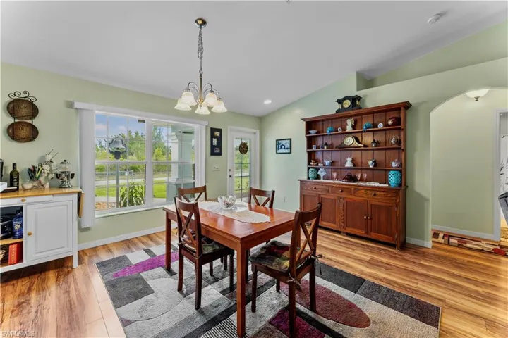 Dining area featuring lofted ceiling, light wood-type flooring, and a chandelier